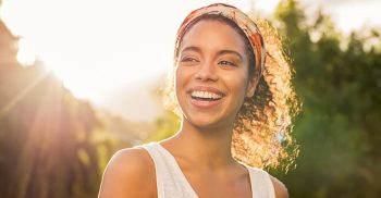 A smiling woman with curly hair expresses joy and laughter, showcasing a cheerful demeanor.